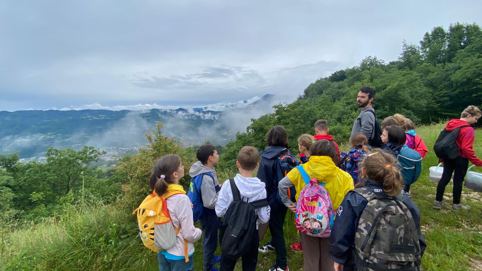 bambini e bambine ammirano il paesaggio delle Piccole Dolomiti in parte coperte dalle nuvole