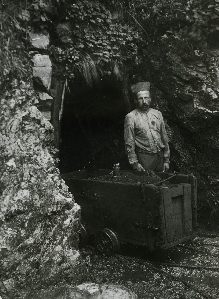 Minatore all'ingresso della galleria Cimani - miniera del Monte Pulli vicino ad un carrello pieno di lignite